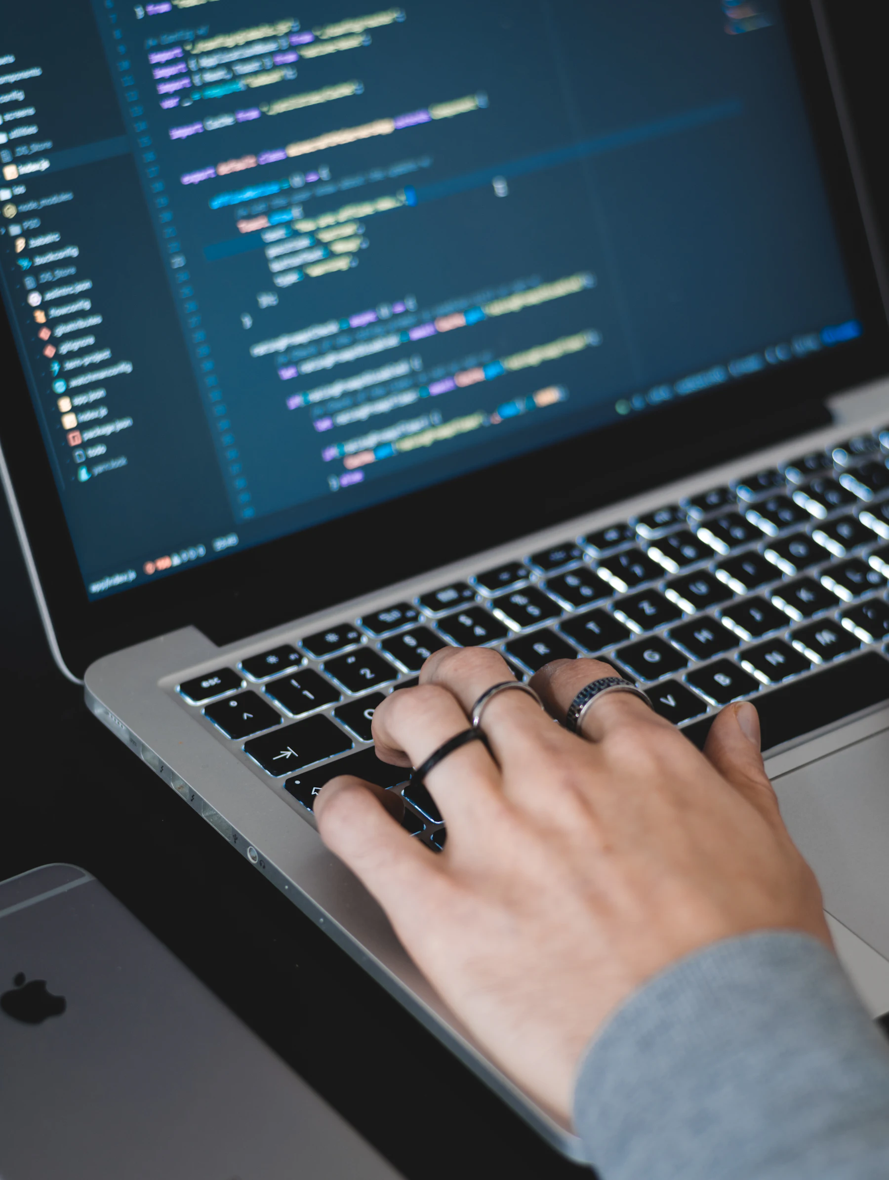 Hands typing on a laptop with code on screen