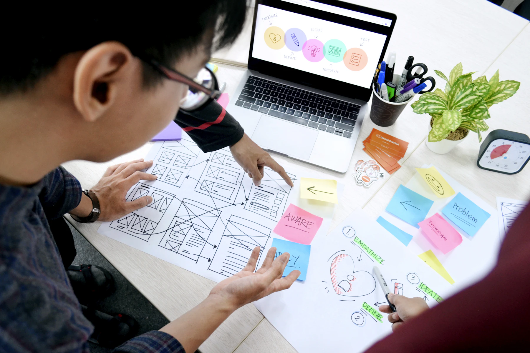 A designer arranging wireframes and sticky notes on a desk