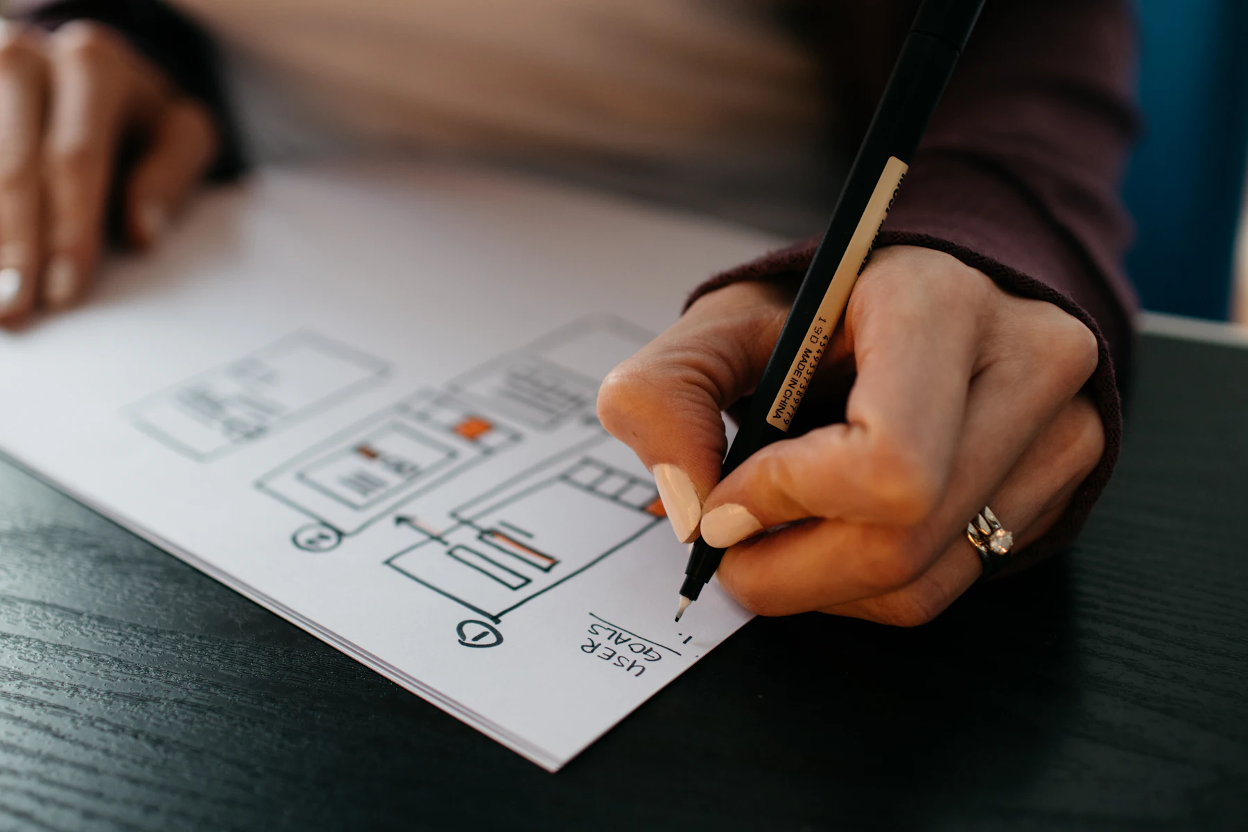 A hand sketching a wireframe on paper