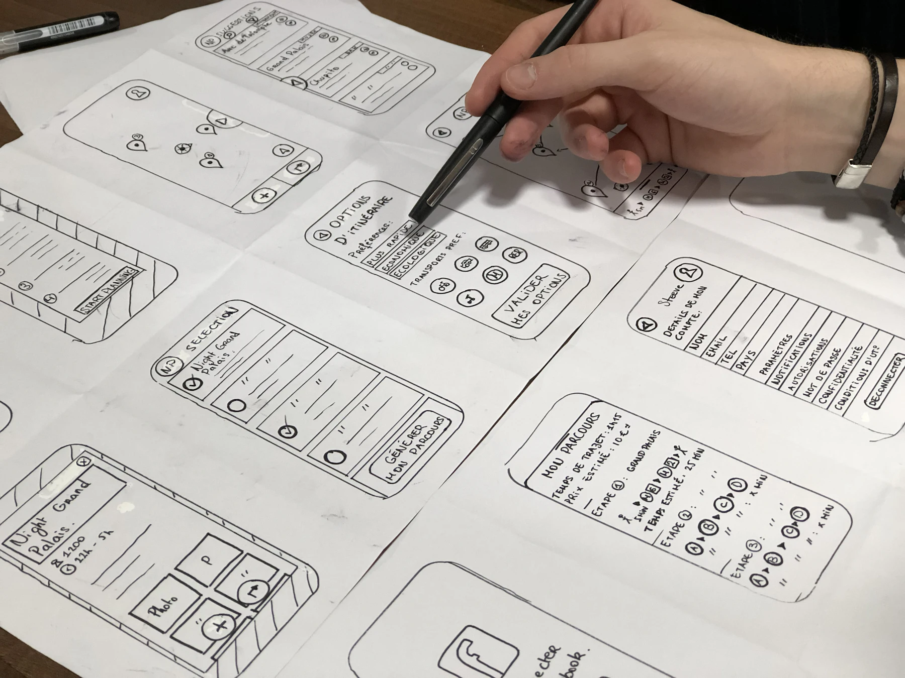 Pages of hand-drawn app wireframes being annotated